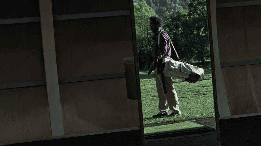 Ein Golfer steht auf dem Green mit einer Golftasche über seiner Schulter.