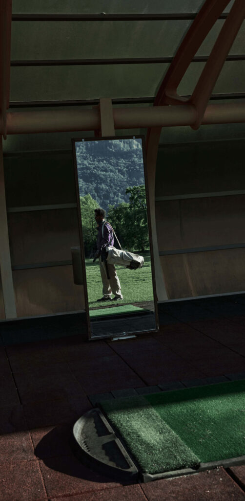 Ein Golfer steht auf dem Green mit einer Golftasche über seiner Schulter.