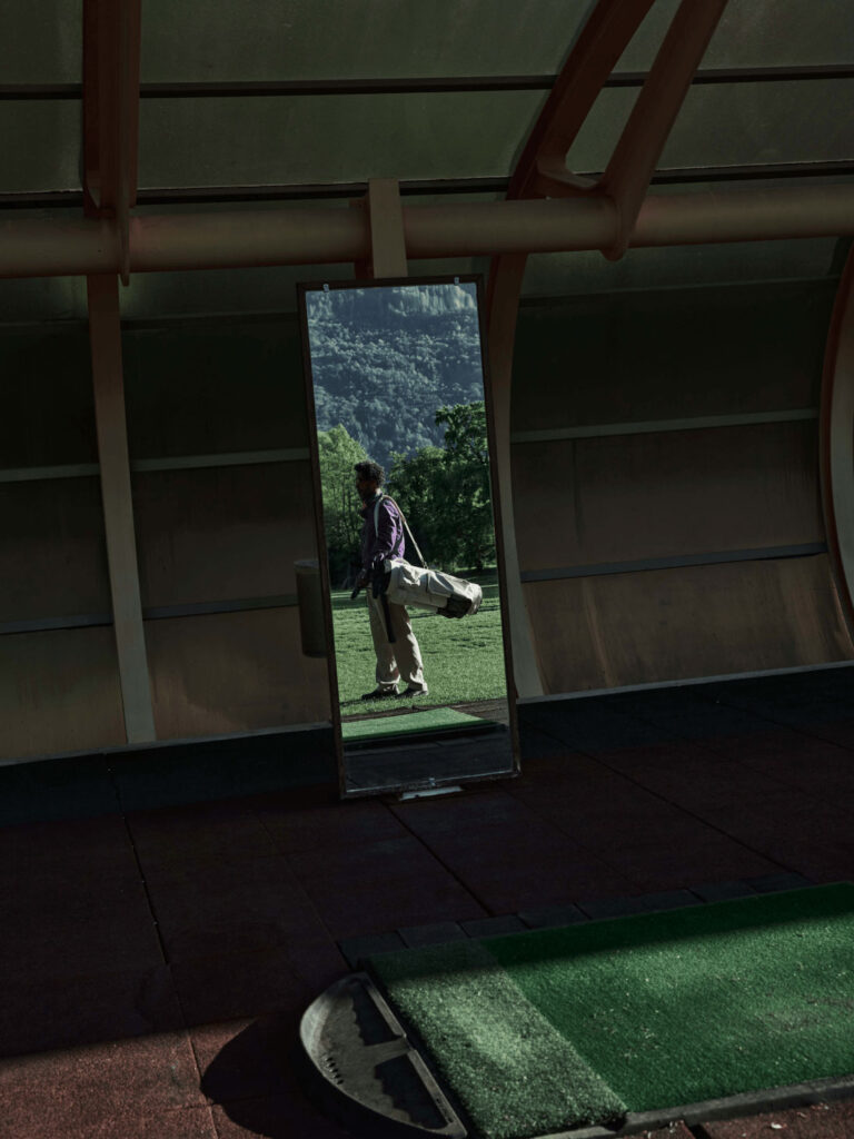 Ein Golfer steht auf dem Green mit einer Golftasche über seiner Schulter.