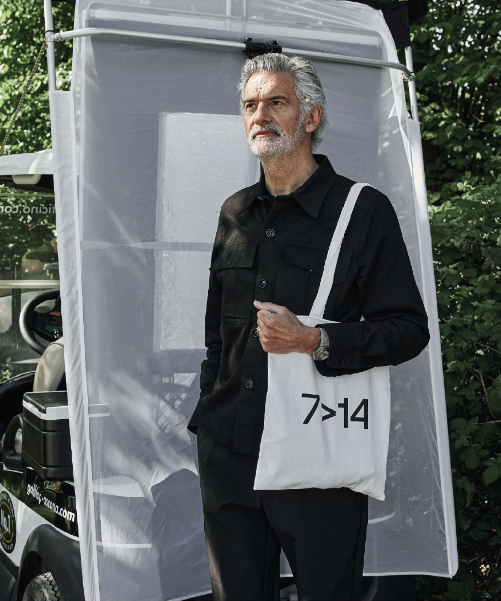 Alfredo Häberli happily standing in front of a golf cart, with the Golfyr bag hanging on his shoulder