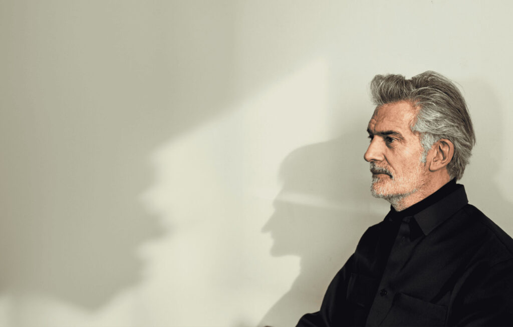 Alfredo Häberli sitting in front of a wall, casting his shadow profile onto it