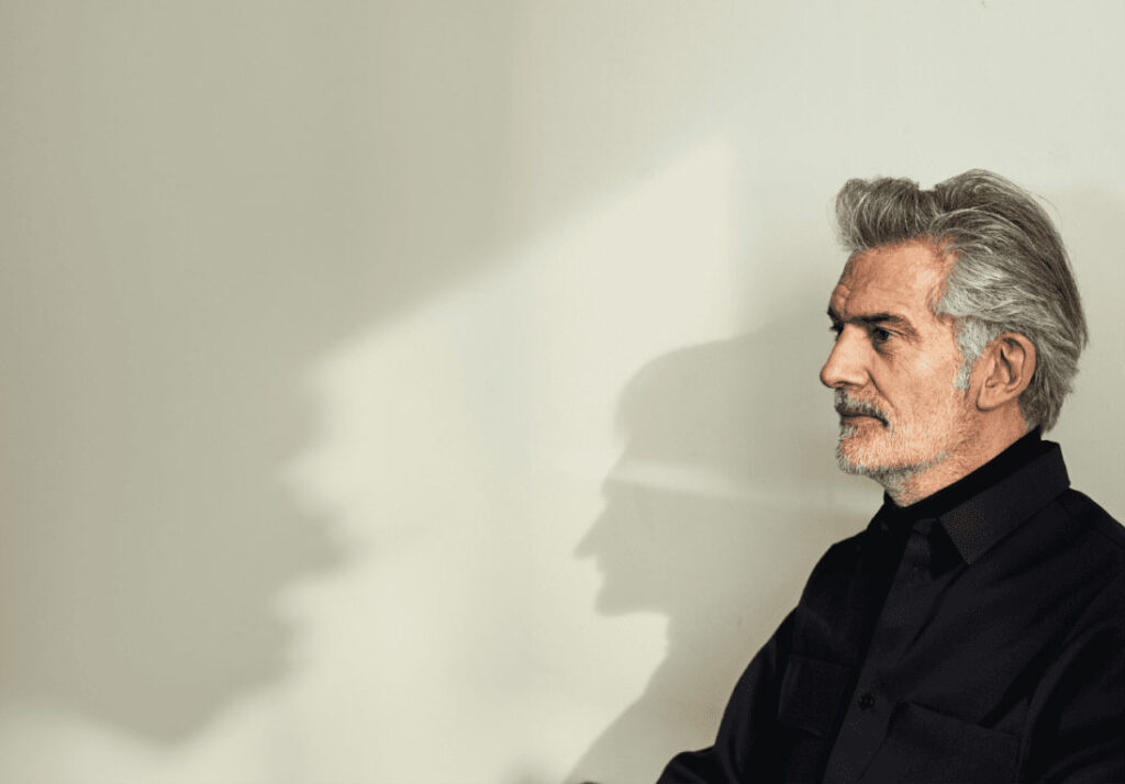 Alfredo Häberli sitting in front of a wall, casting his shadow profile onto it