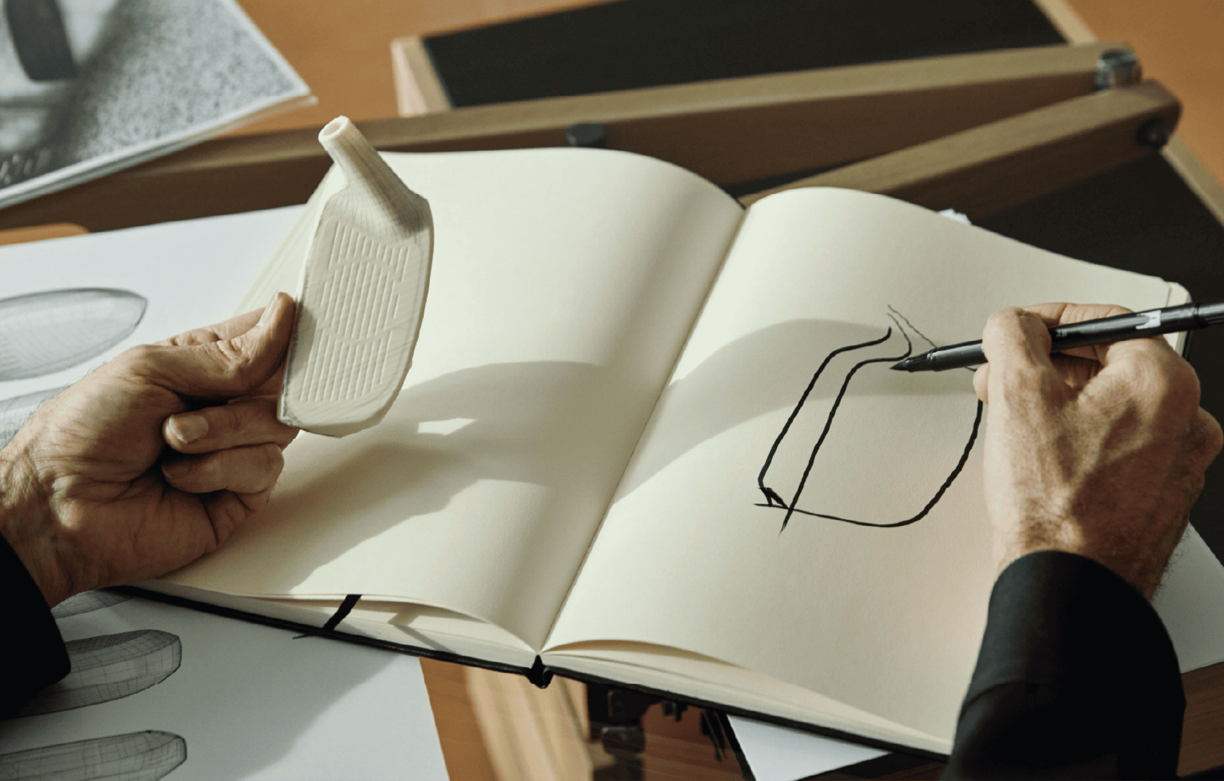 Alfredo Häberli hält einen Schläger-Prototypen in einer Hand und zeichnet ihn mit der andere Hand