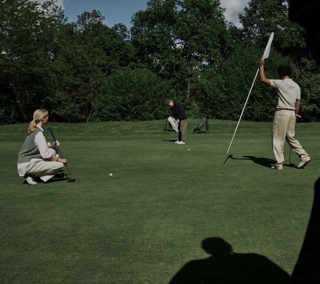 Two golfers and Olivier Widrig putting on the green