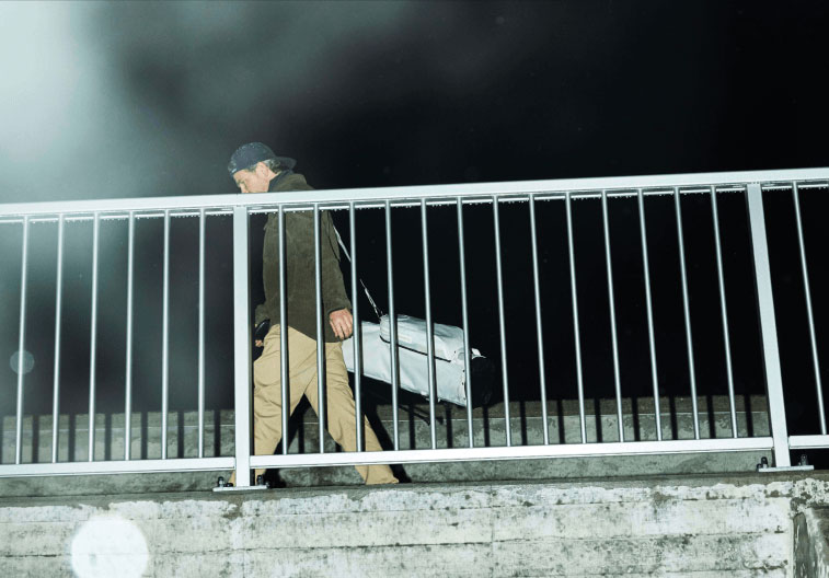 Olivier Widrig walks behind a fence with his golf bag around his shoulder